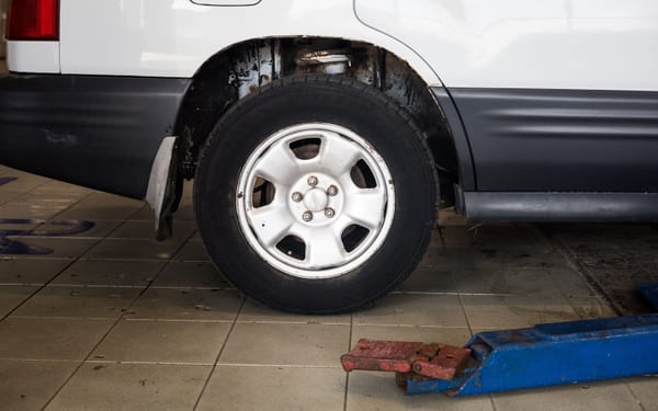 A car raised on a floor jack in a repair shop