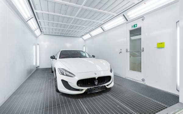 A car inside a modern, empty paint booth