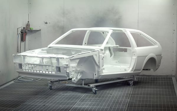 A bare, primed car body shell in a paint booth