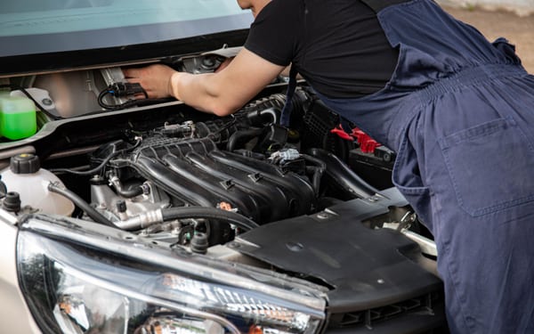 A mechanic working in an open engine bay in daylight