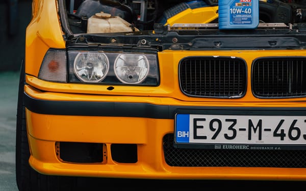 An open car hood with a bottle of motor oil in the engine bay