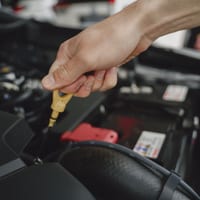 A hand holding a yellow engine oil dipstick