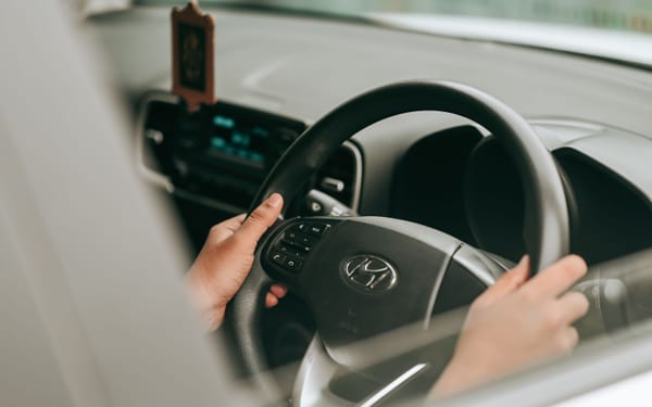 Hands holding a car steering wheel while driving straight