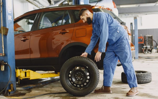 A mechanic changing a wheel on a car in a shop